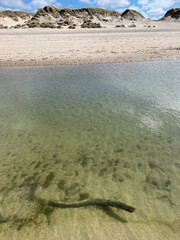 Wasserfläche eines Priels bei Flut mit Überblick über den Nordseestrand und die Dünen