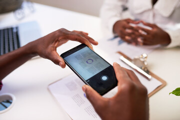A Black man takes a photo of the financial document to scan it