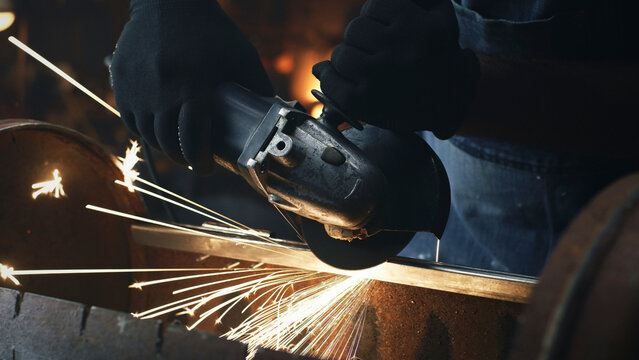 Close Up Shot Of Man Processing And Grinding Metal Barbecue Bbq Grill In Workwear And Protective Gloves In Equipped Garage Workshop