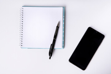 Notepad, blank sheet and phone on a white background. Top view.