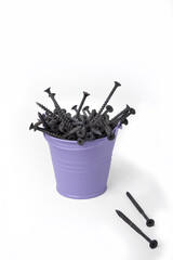A bucket full of black self-tapping fasteners on a white background. Isolated.