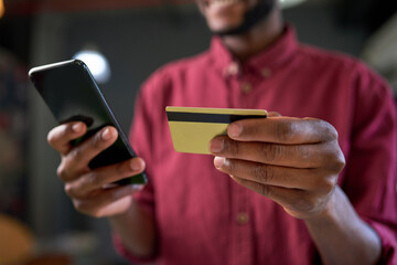 A close up of hands holding credit card and cellphone online shopping