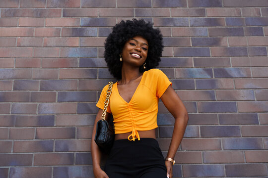Portrait of young black woman with afro hairstyle smiling in urban background