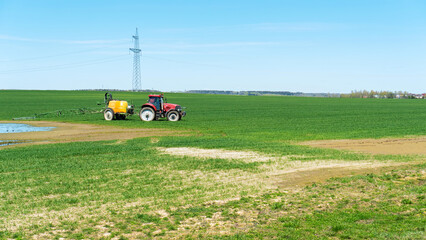 A tractor sprays a field of crops with glyphosphate to remove weeds. Fertilization of crops with...