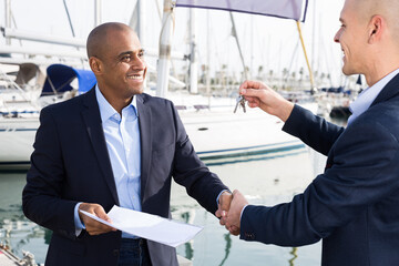 Latin American men with documents and keys near the yachts in the port