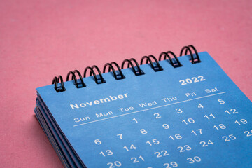 November 2022 - small spiral desktop calendar against textured  paper, low angle macro shot, time...
