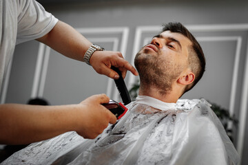 Male client getting haircut by hairdresser in barbershop