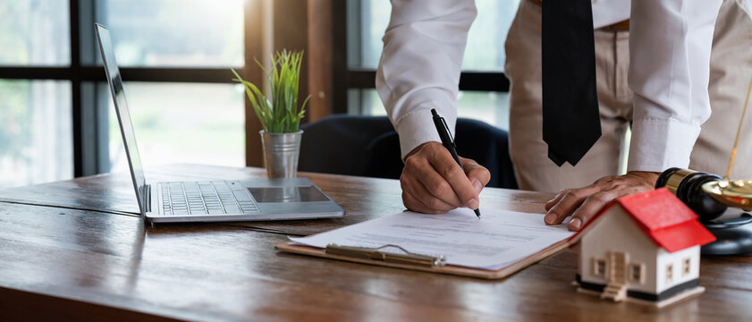 Close up young businessman standing near table with pen in hands, ready signing profitable offer agreement after checking contract terms of conditions, executive manager involved in legal paperwork..