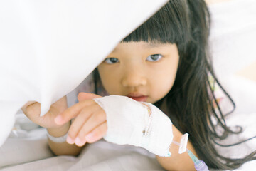 Asian child admitted in hospital with saline intravenous on hand
