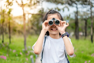 Children travel in flower field and holding binoculars on green nature background