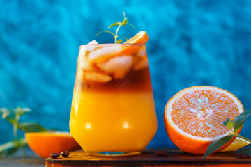 cold bumble coffee. refreshing espresso coffee with orange juice and ice on a blue background. Orange slices