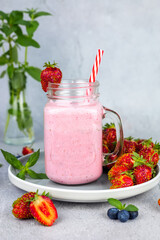 Strawberry lassi or milkshake on gray background. Healthy milky Indian drink.