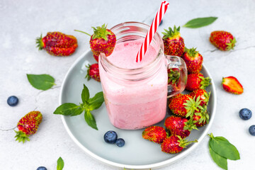 Glass of delicious strawberry smoothie with mint on gray concrete table