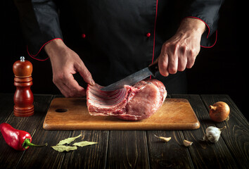 Hands of a butcher with a knife in the kitchen. Cooking delicious food for the hotel. Cooking raw pork ribs
