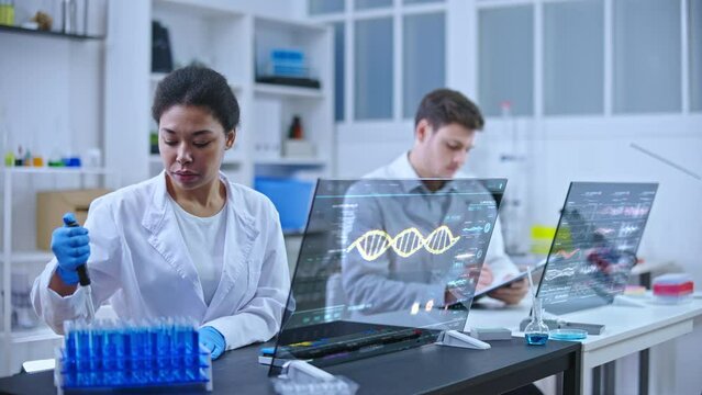 Lab technician dripping sample substance into flasks, dna sequence on screen