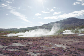 Geyser Park in Iceland. Stones on ground. Steam from geyser under ground