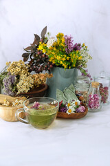 Glass tea cup and set of fresh and dry useful herbs on table, abstract marble background. Healthy medical Herbs collection. Homemade herbal vitamins tea for  remedy for flu and cold