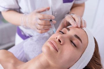 Obraz na płótnie Canvas portrait of a young woman receiving facial mesotherapy treatment to smooth wrinkles. an anti-aging injection to firm up the skin