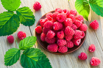 Fresh ripe raspberries in a plate on a wooden table
