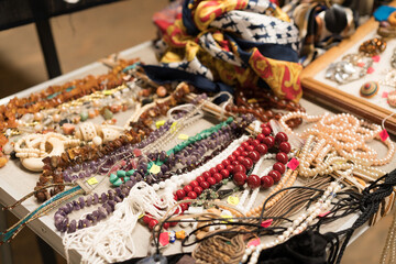 Various antiques at flea market or garage sale - vintage jewelry, retro pearl and gemstone necklace, other vintage things. Collectibles memorabilia concept. Selective focus