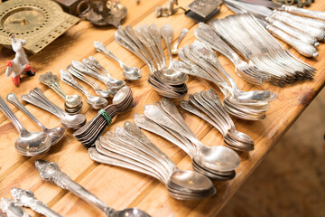 Antiques at flea market or garage sale, aged vintage silver cutlery - spoons, knifes, forks, and other vintage things. Collectibles memorabilia and garage sale concept. Selective focus