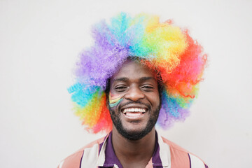Happy african gay man with rainbow color wig smiling on camera at LGBT pride parade