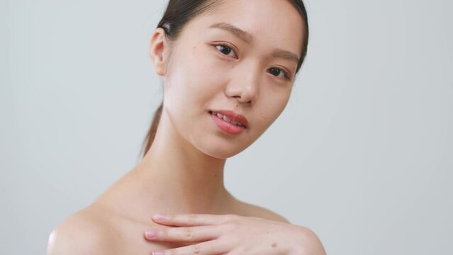 Portrait young Asian woman touching health body skin over grey background.