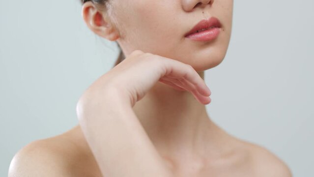 Portrait young Asian woman touching perfect neck skin over grey background