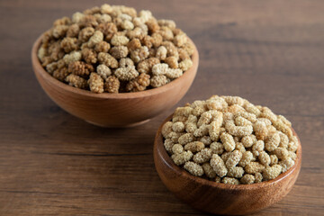 Bowl full of dried mulberry on a wooden background
