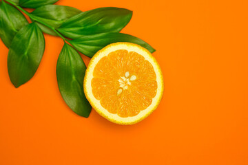 Ripe juicy orange and green leaves on bright orange background. Orange fruit, citrus minimal concept. Creative summer food minimalistic background.