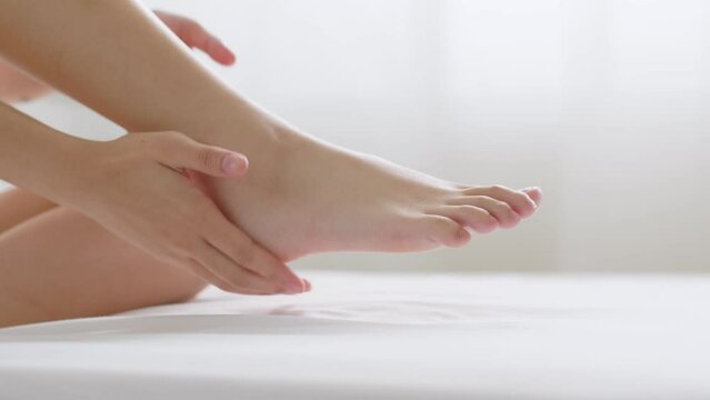 Close up young Asian woman applying lotion and skincare cream for dryness skin on foot heel