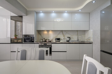 Interior of modern trendy white kitchen, front view