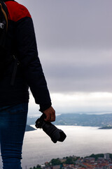 Unrecognizable photographer with camera in hand and in the background the city of Bergen and the fjord in Norway.