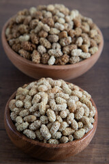 Bowl full of dried mulberry on a wooden background
