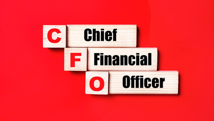 On a bright red background, wooden cubes and blocks with the text CFO Chief Financial Officer. Manufacturing of wooden toys.