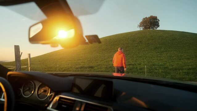 A young man gets out of the car after taking a wrong turn. Got lost on the road trip concept, went the wrong way and checked his surroundings.
