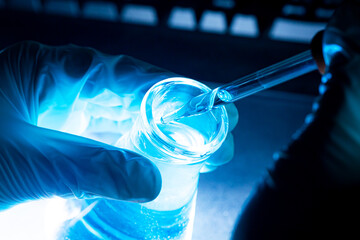 Blue science experiment glass tube,Researchers with chemistry test tubes in a liquid glass lab for...