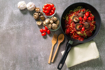 spaghetti in pan,Tasty appetizing pasta served with tomato sauce, fresh tomatoes, basil and cheese in pan on blue table. View from above