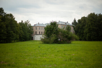 Fototapeta na wymiar Building in park. Old building among trees. House stands at end of park. Green lawn.