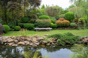 Bamboo seat to sit and relax beside the path in japanese green garden. Relaxation vibe outdoor of garden design decoration concept. A place for relaxing. 