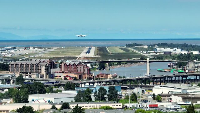 Airplane Arriving At Vancouver International Airport With Traffic On Road Bridge On Sea Island In Richmond, BC, Canada. - slider