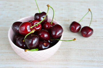 fresh garden cherries in pink bowl isolated on pastel background