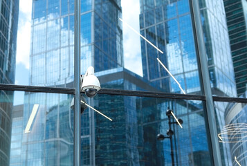 Naklejka premium Public CCTV camera on modern building exterior. Recording camera for monitoring. Concept of surveillance and monitoring in the business and financial center of the city. Financial security and control