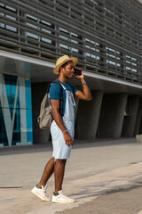 successful casual black man standing talking on mobile phone against a corporate backdrop with windows