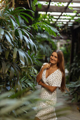 Female gardener at a plant nursery in Bali. Young caucasian woman working in a garden center. Woman in palm greenhouse of the Botanical garden