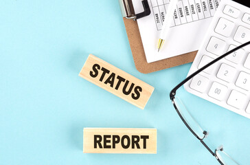 STATUS REPORT text written on wooden block with clipboard ,eye glasses and calculator Business concept.