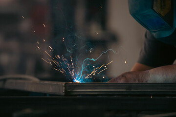 Industry worker welding iron pieces at work