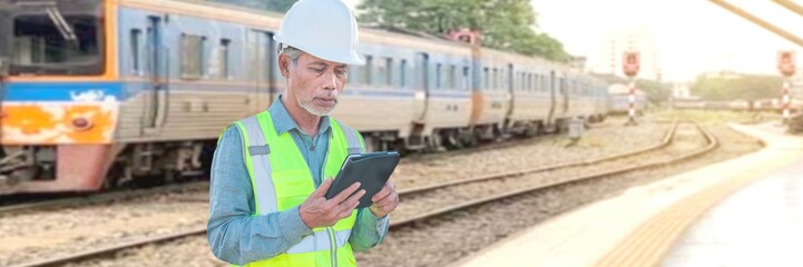 Professional railway engineer workers wearing safety suits and hard hats use tablet computers. A...
