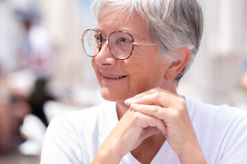 Portrait of beautiful senior mature woman sitting at outdoor restaurant table looking away