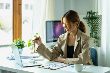 Young beautiful Asian woman working with a laptop while sitting at office desk, working from home concept.
